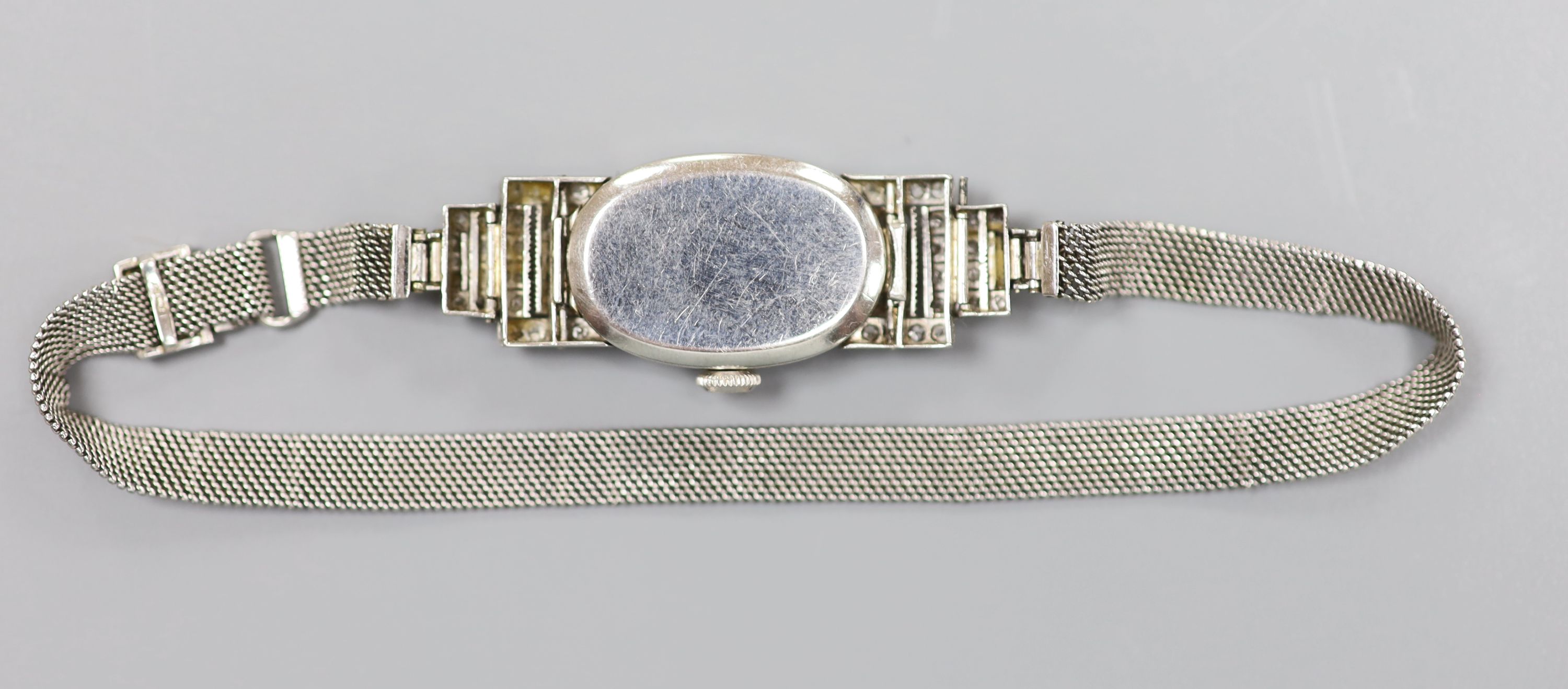 A lady's mid 20th century white metal (stamped platinum) and diamond set cocktail watch, with tumbling numerals, on an 18ct mesh link strap